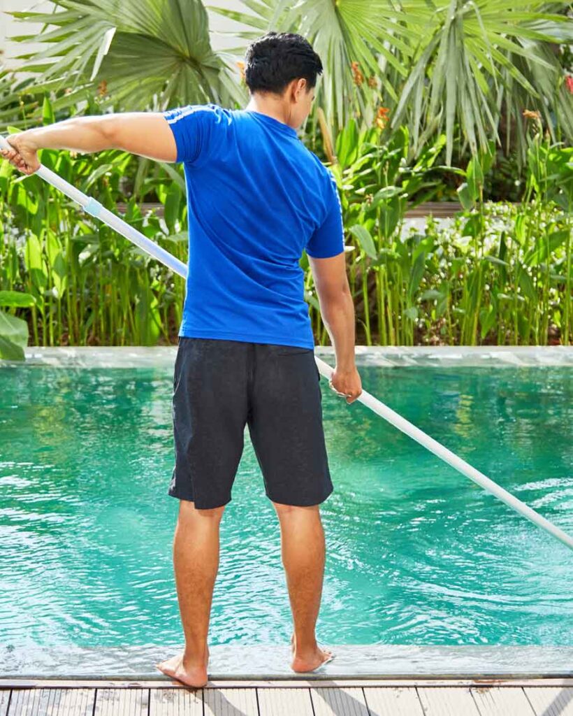 Young man with blue shirt cleaning a swimming pool